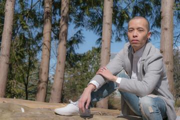 切り株に座る坊主の細身の男性