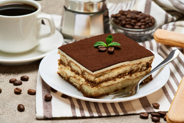 Portion of Traditional Italian Tiramisu dessert and savoiardi cookies on grey concrete background