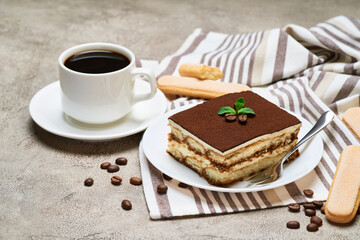 Portion of Traditional Italian Tiramisu dessert and savoiardi cookies on grey concrete background