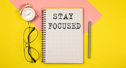 Stay focused on the notepad with pen, glasses and alarm clock