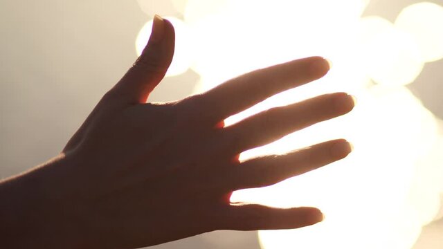 Closeup view 4k stock video footage of outstretched empty female hand isolated at golden blurry sparkling with magic sunset spring sun light water background