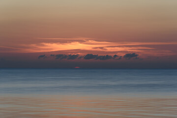 sunset at the ocean with cloudy orange sky