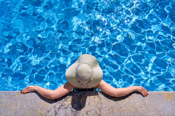 A girl in a hat is resting in a beautiful pool. Vacation concept