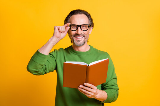 Photo of guy hold textbook look camera shiny smile wear green pullover isolated yellow color background