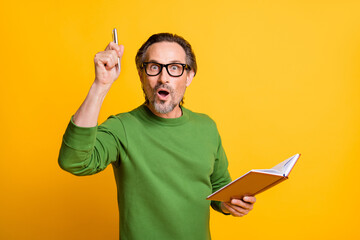 Photo of genius clever writer hold copybook pen shocked open mouth wear glasses green pullover isolated yellow color background - obrazy, fototapety, plakaty