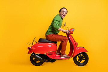 Fototapeta na wymiar Photo of crazy man ride moped travel enjoy wear glasses green pullover pants footwear isolated yellow color background