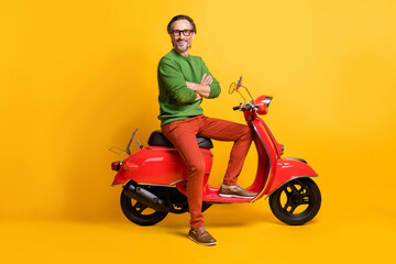 Fototapeta na wymiar Photo of self-assured man ride moped crossed hands wear eyewear green sweater pants footwear isolated yellow color background