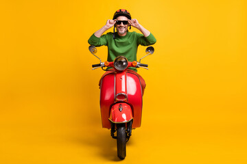 Photo of cheerful guy drive bike wear helmet sunglass green sweater isolated yellow color background
