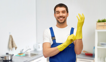 profession, cleaning service and plumbing concept - happy smiling male worker, plumber or cleaner in overall wearing gloves over home room background