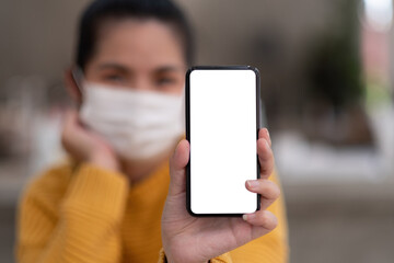 Mockup image of a beautiful woman wear mask while holding mobile phone with blank white screen.