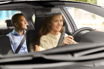transportation, vehicle and people concept - happy smiling female driver driving car with male passenger
