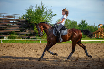 A girl rider trains riding a horse on a spring day.