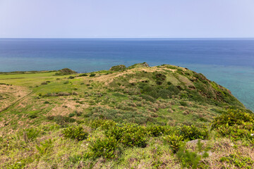 Fototapeta na wymiar 石垣島最北端の平久保崎で新緑の丘陵地からコバルトブルーの海を眺める