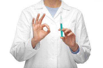 medicine, vaccination and healthcare concept - close up of female doctor or nurse with syringe showing ok hand sign over white background
