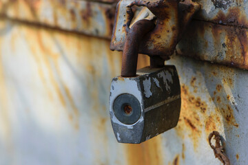 Rusty old padlock on metal gate closeup. Dirty lock on closed Grey painted front door. Protection, security and safety concept. Private property entrance. old rusty iron texture. space for text