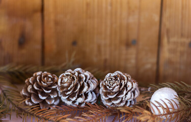 Fir cones and fir branch out of focus on the background of wooden boards, preparation for Christmas greetings, copy space for text
