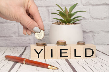 Yield a word on wooden dice and coins in your hand on a wooden table. Harvest profit business concept