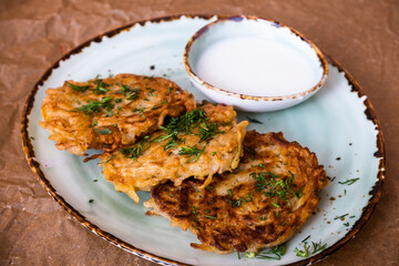 Belarusian national food. Photo of potato pancakes with sour cream sauce. Restaurant menu. Hearty breakfast.