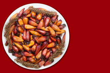 Natural pinion nut, fruit of the Araucária angustifolia tree (Pinheiro do Paraná), a prehistoric tree. Top view on red background. Winter gaucho tradition