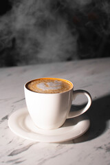 a cup of coffee with milk foam on the table. steam from coffee