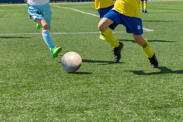 Children's football. An interesting football moment at the match and training. The active struggle and dynamics of the boys' soccer match. The boys are recklessly fighting for the ball