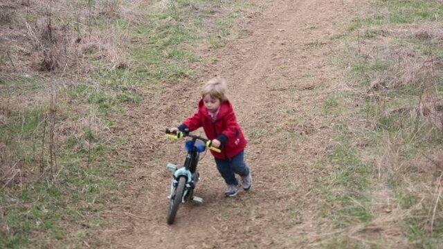 Little boy, learning how to ride a bike in the park, springtime