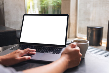 Mockup image of a woman using and touching on laptop touchpad with blank white desktop screen while drinking coffee