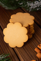Gingerbread cookies in a stack on a wooden background and spruce branches in the back. Traditionally a Christmas treat.