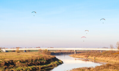 Paralotnia nad rzeką latająca przy zachodzie słońca - obrazy, fototapety, plakaty