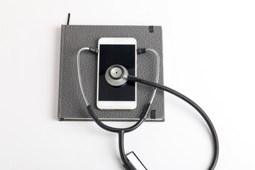 Smartphone and stethoscope on white background. Online medicine (telemedicine) technology. Service for remote diagnostic, chat with doctor.