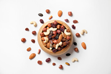 Different types of nuts in a wooden bowl and scattered on isolated white background. Nutrient dense vegan snacks. Clean eating concept. Close up, copy space for text, top view, flat lay.