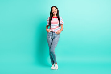 Fototapeta na wymiar Full size photo of nice brunette optimistic long hairdo lady stand wear t-shirt jeans sneakers isolated on teal color background