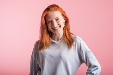 Beautiful young redhead girl in the studio on a pink background