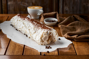 Close-up shot of meringue roll with coffee filling sprinkled with powdered sugar