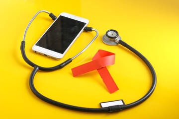 Smartphone and stethoscope on yellow background. Online medicine (telemedicine) technology. Service for remote diagnostic, chat with doctor.