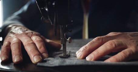 Macro shot of experienced tailor is sewing custom handmade high quality apparel in ancient luxury traditional tailoring workshop. Concept of industry, handmade, hand craft, couturier and tradition.