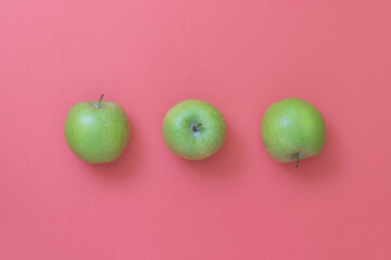 Green natural apples on pink background