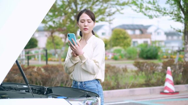 自動車のボンネットを開ける女性　故障　ロードサービス