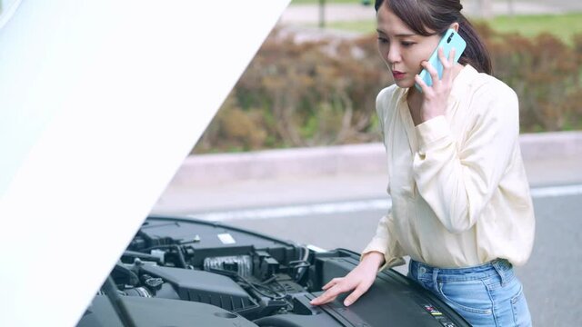 自動車のボンネットを開ける女性　故障　ロードサービス