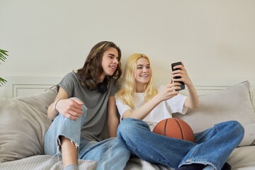 Happy laughing hipster teenagers male and female having fun using smartphone