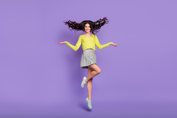 Fototapeta na wymiar Full size photo of optimistic nice brunette curly lady jump wear sweater skirt sneakers isolated on purple color background