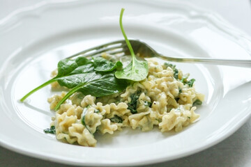 Mafalde Pasta with Mascarpone cheese sauce and spinach on a white plate with a silver fork