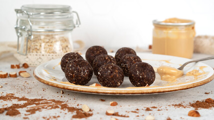 Super food energy balls. Homemade healthy raw vegan dessert on white plate with oatmeal and peanut butter. Healthy eating. Fitness snack. Selective focus