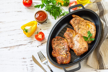 Barbecues parties menu. Baked meat pork loin on the bone with spices in a cast iron pan on rustic wooden table. Copy space.