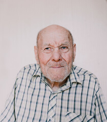 a large portrait of an old man on a light background with deep wrinkles, age spots.
