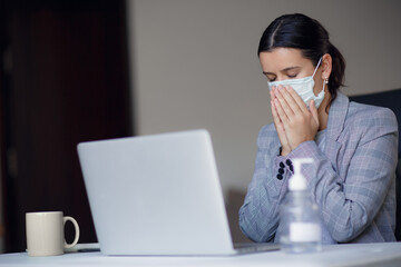 Sick, ill unhealthy female employee coughing or sneezing while working in workplace in office. Spreading and risk of corona virus covid-19 in workplace.