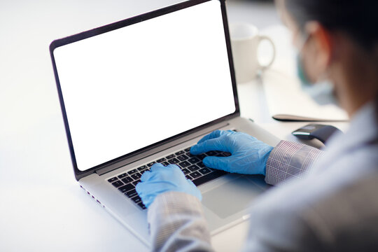 Young woman wearing protective gloves and mask on face working from office or home using laptop. Computer empty blank screen. Copy space for text. Preventing corona virus spread