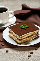 Portion of Traditional Italian Tiramisu dessert and savoiardi cookies on grey concrete background