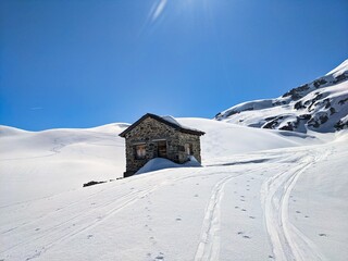 old customs hut between the austrian and swiss border on the plasseggenpass. Sunny ski tour in the mountains. blue sky
