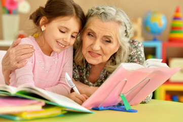 Grandmother with cute little girl doing homework